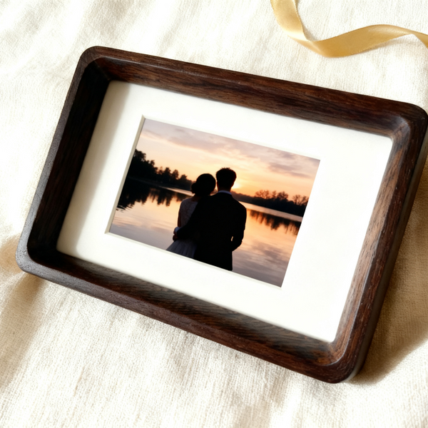 Wooden photo frame with a silhouette of two people at sunset on a lake.